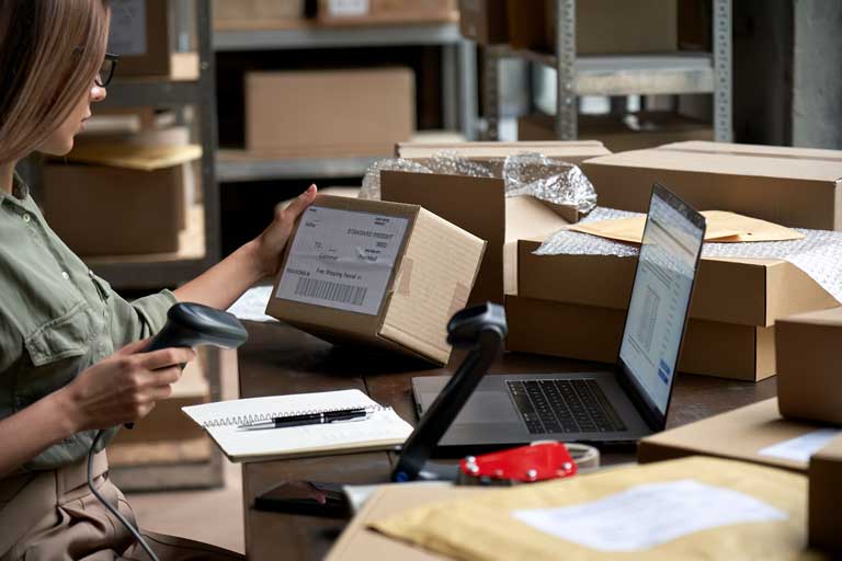 Woman running her own ecommerce business scanning a label on a package