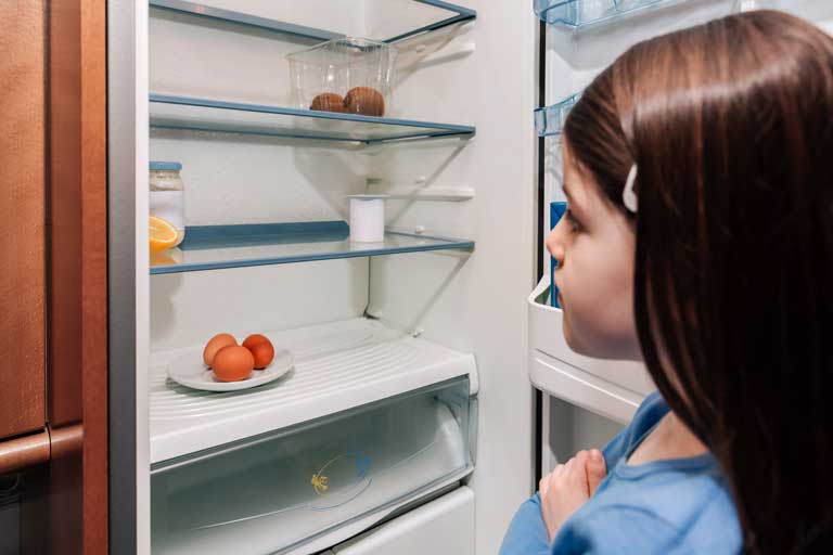 Girl looking at empty fridge due to a crisis