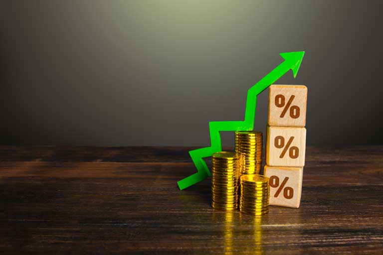 Coins, wooden blocks with percentages engraved and a green arrow on top simulating higher interest rates