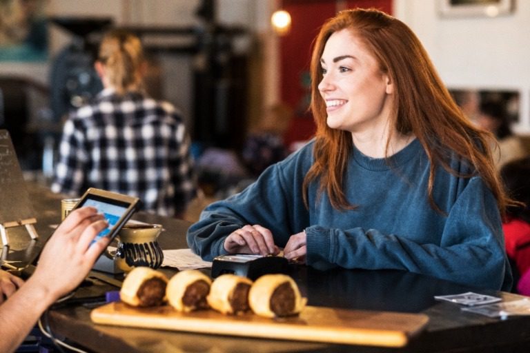 Woman with red hair paying for food at a bar