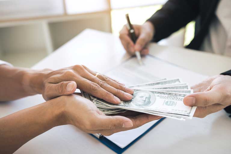 Mens hand grabbing cash being handed to him by a loan officer