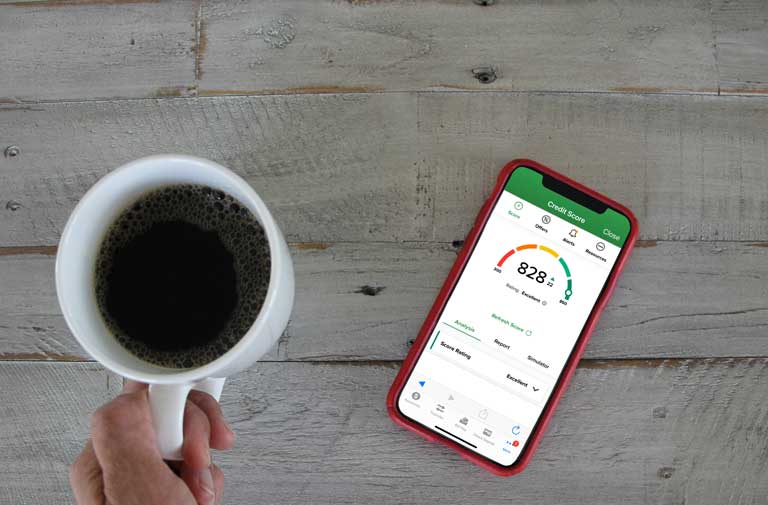 Person having a coffee checking their credit score on a phone screen