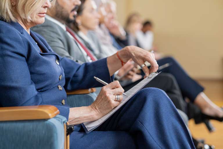 Row of foreign delegates sitting down at a lecture while writing notes