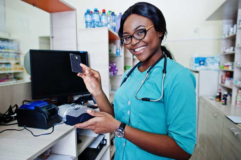 Smiling african american nurse using a customer's credit card to make a payment inside a pharmacy