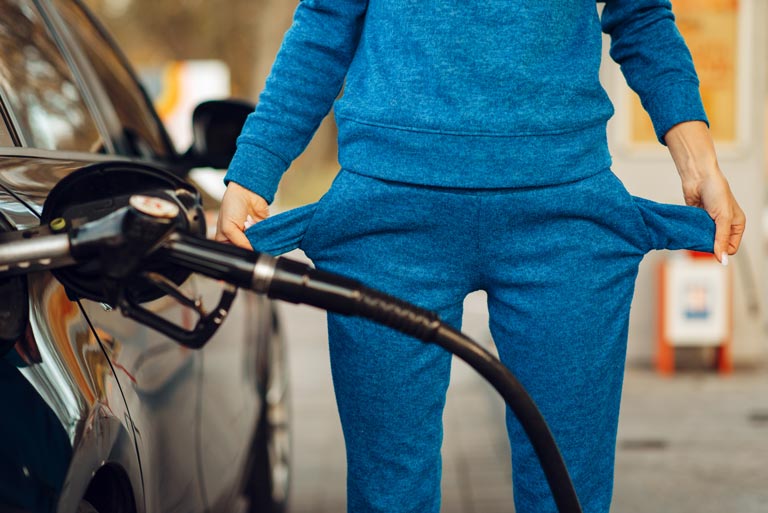 Female pumping gas at a gas station while holding out her empty pockets