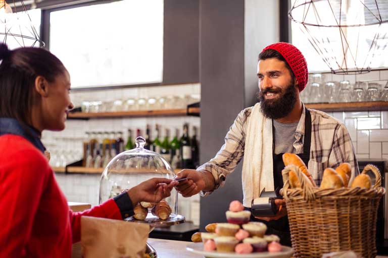 Cafe owner holding receiving a customer's credit card paying for her drink