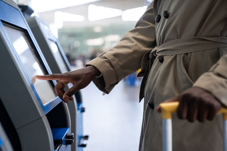 African american man checking in at an airport through a self service kiosk