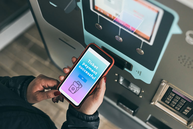 Woman paying for a ticket stub with her phone at a payment kiosk