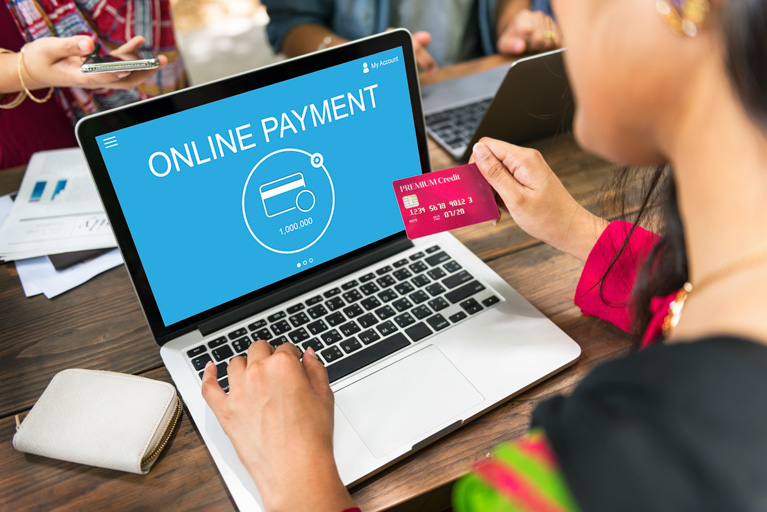 Woman holding a credit card about to make an online purchase on her laptop