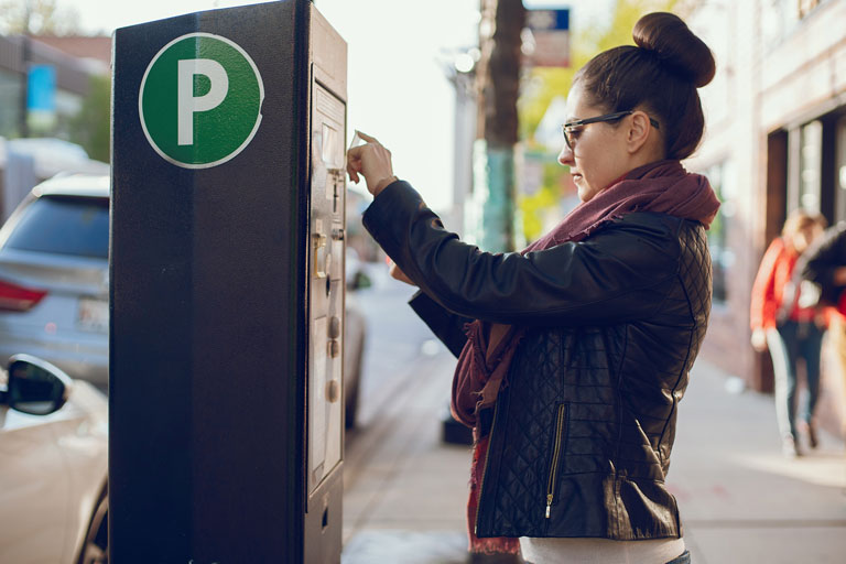 Woman paying for parking at a parking kiosk
