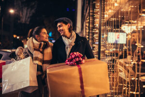 Couple carrying holiday gifts walking in front of a store