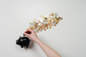 Woman putting money inside a black piggy bank