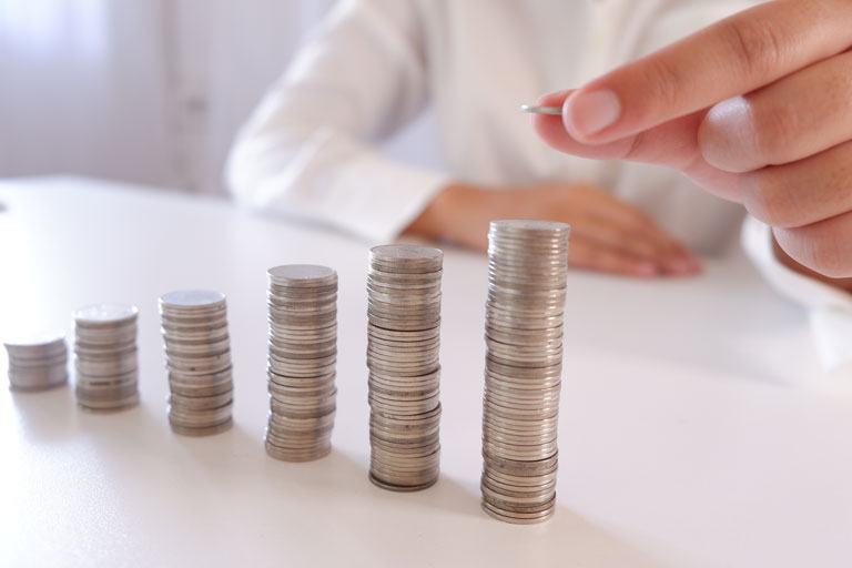 Woman adding coins to a coin stack on a table