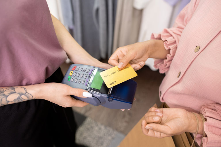 Woman at a clothing store holding her credit card over a payment terminal