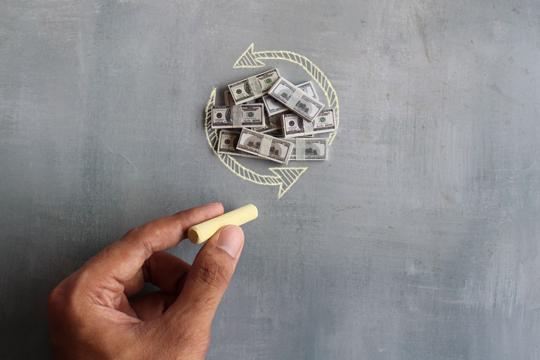 Man drawing a circle around stacks of cash