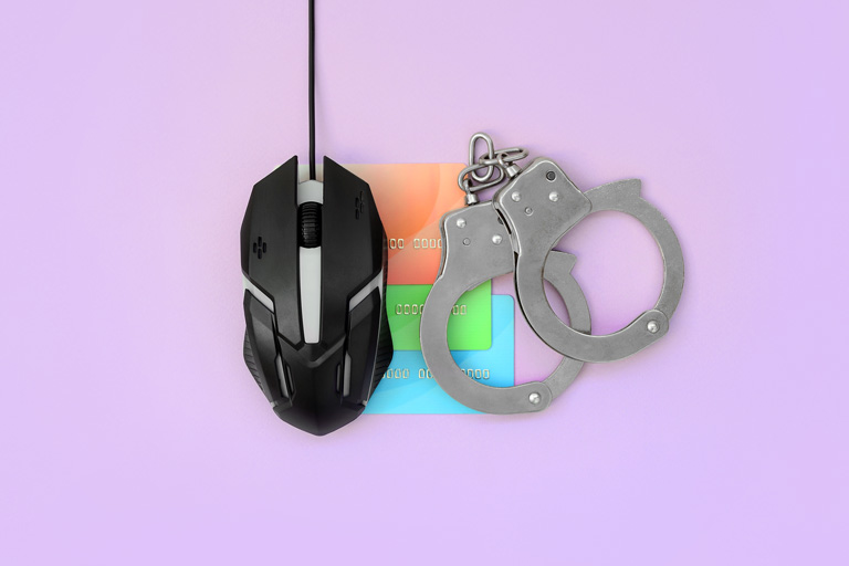 Computer mouse next to 3 credit cards and handcuffs