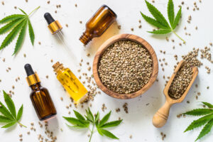 Cannabis seeds on a wooden bowl and jard os CBD oil on top of a table