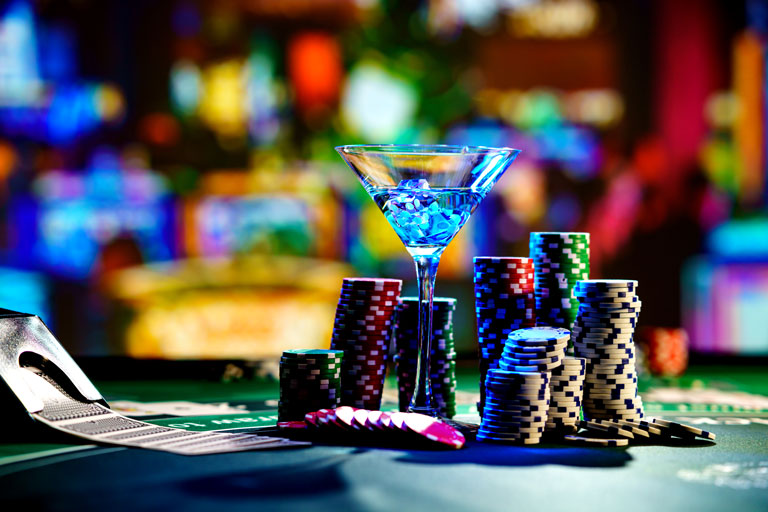 Cocktail glass, poker chips and cards on top of a poker table at a casino