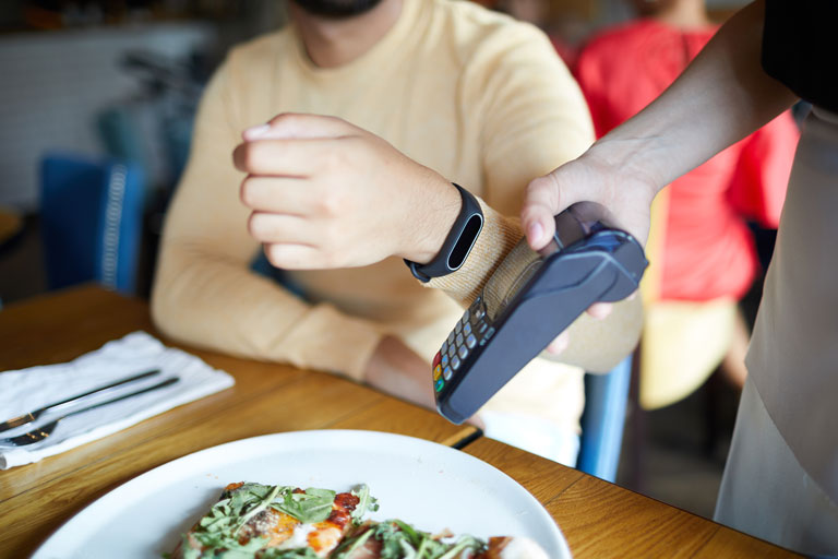 Men paying at a restaurant with a smartwatch