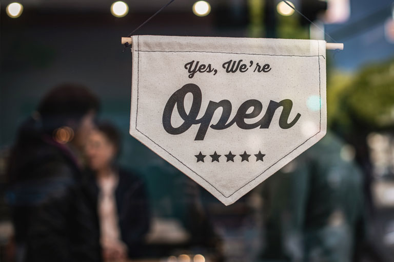 Yes we're open sign hanging at the entrance of a restaurant