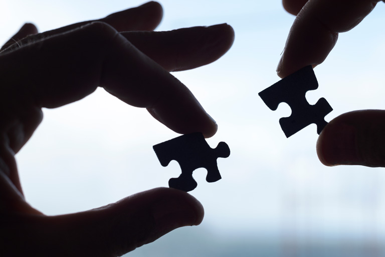 Two hands holding puzzle pieces