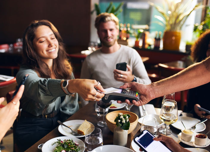 Young female paying with a credit card for a meal at a restaurants with her friends