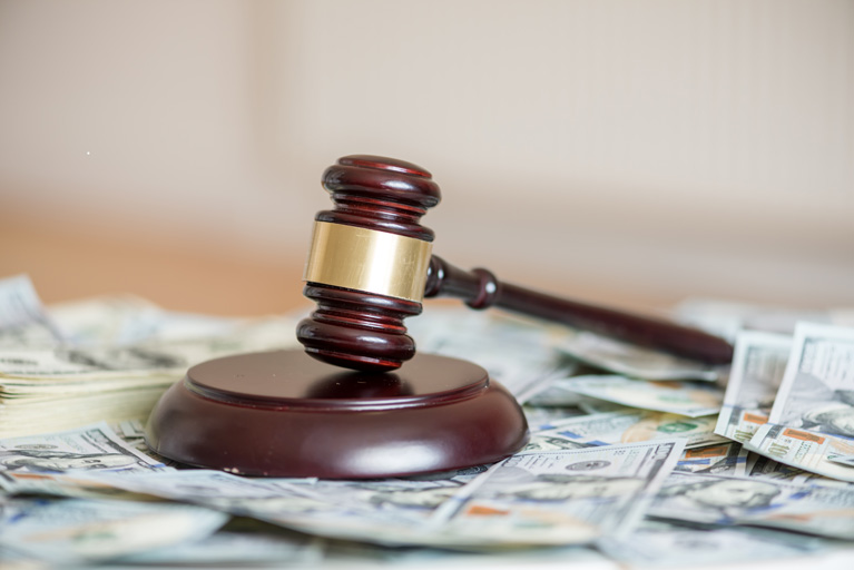 Gavel standing on top of several us dollar bills