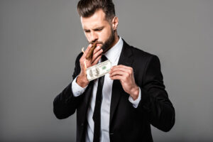 Man in black suit lighting up a cigar with a burning dollar bill