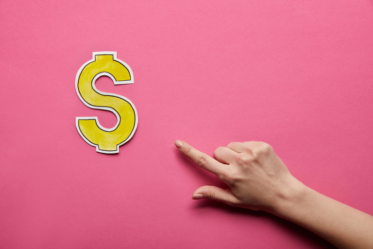 Woman's hand pointing at a yellow dollar sign made out of paper