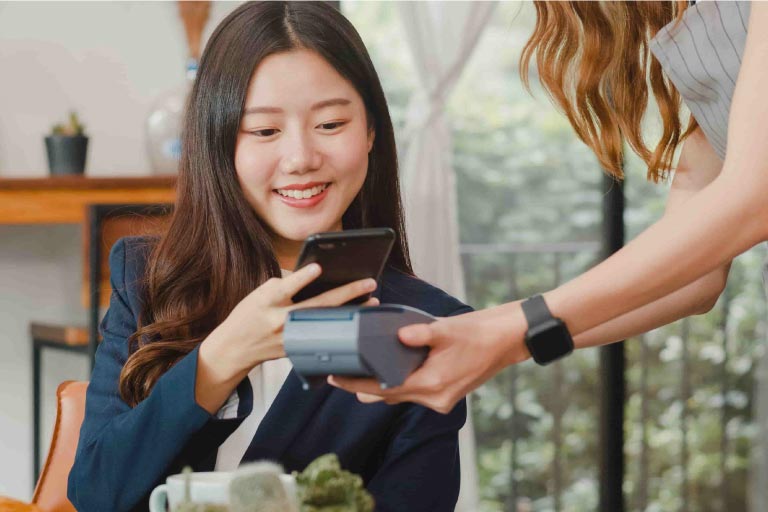 Young Asian woman paying with her phone.