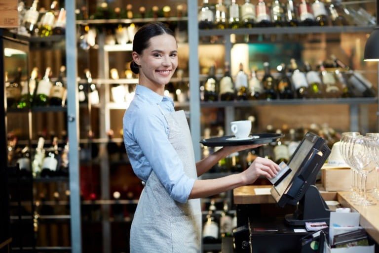 A smiling waitress using a POS system.