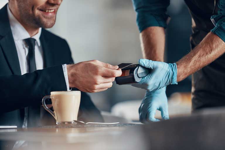 Men paying for a coffee at a restaurant via contactless payment