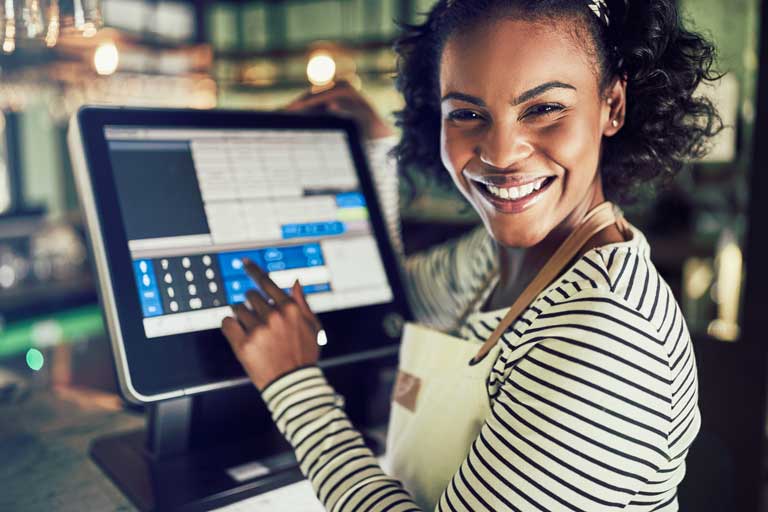 A smiling waitress using the POS system at her restaurant