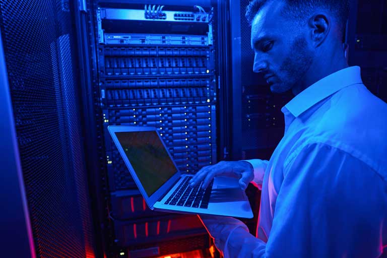 IT technician inside a server room checking the status of an online server