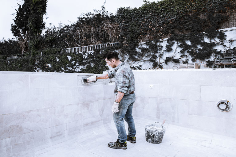 Man applying cement to the inside of a pool