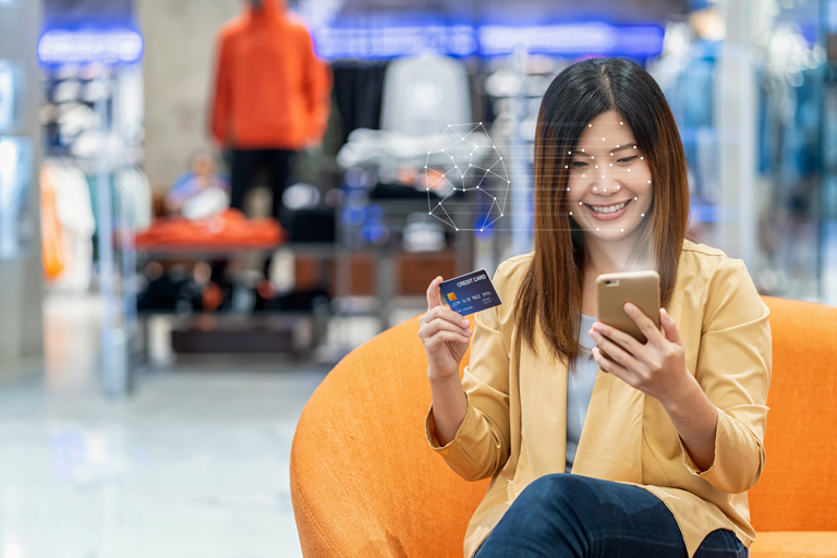 Asian woman unlocking her phone with facial recognition technology to make a purchase on her smartphone