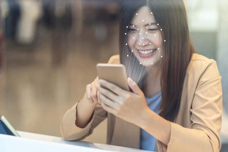 Asian woman unlocking her phone with face recognition technology