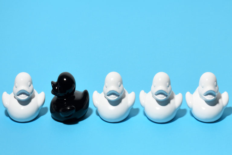 5 rubber ducks in a row, 4 are white one is black