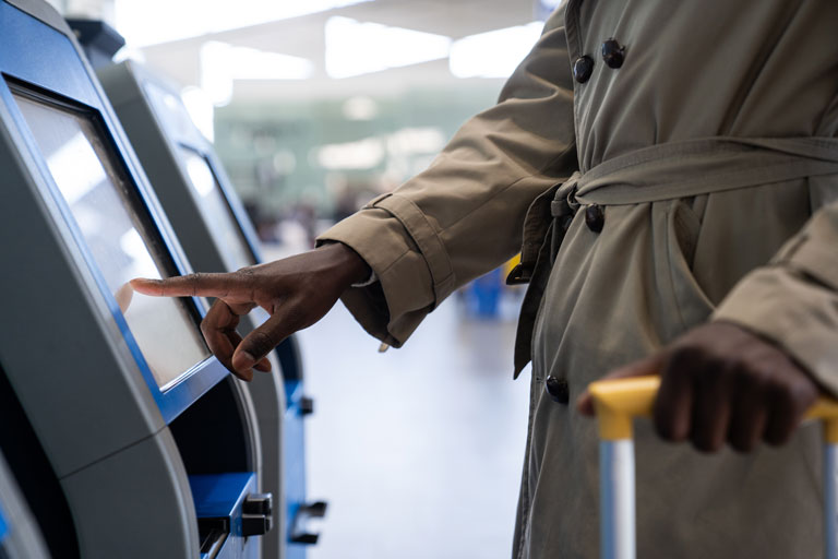 African american man checking in at an airport through a touchscreen self service kiosk