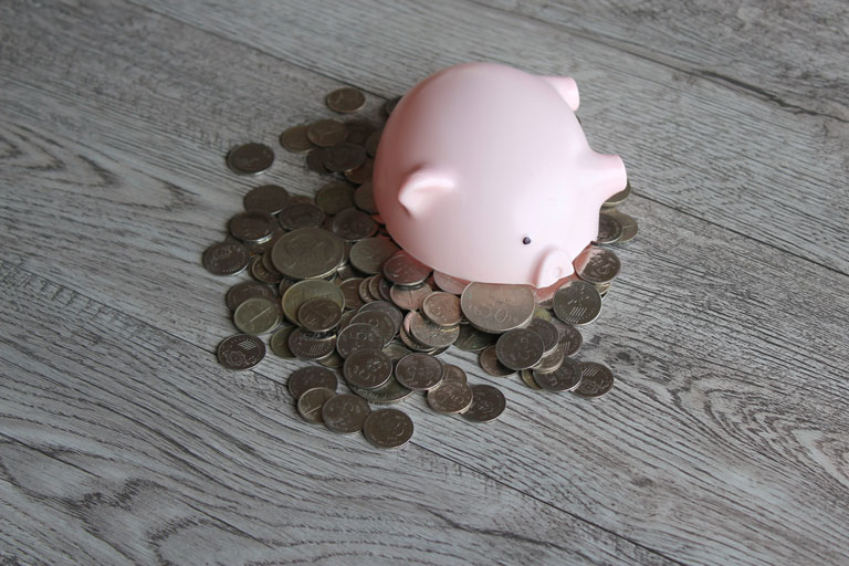 Broken piggy bank on the floor with coins spread across the floor