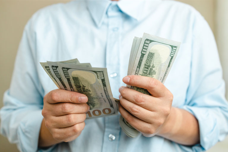Male with a blue shirt counting $100 us dollar bills