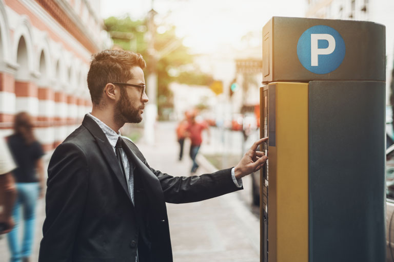 Businessman paying for a parking ticket at a parking meter kiosk