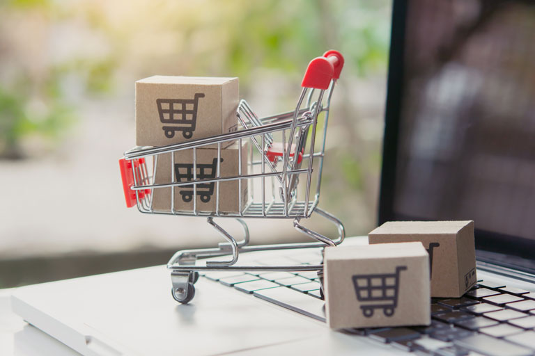 Render of a small shopping cart with shipping boxes inside on top of a laptop's keyboard