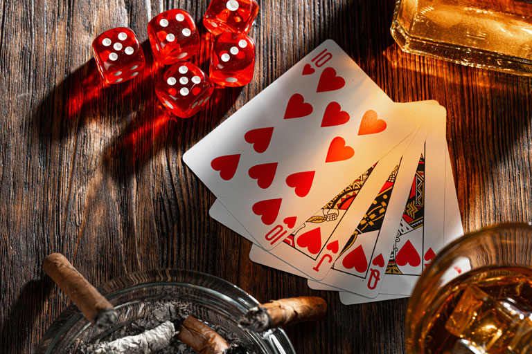 Cigars, playing cards, dice and whiskey on top of a table