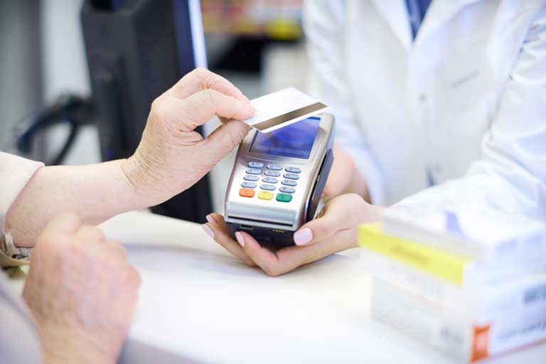 Older woman paying for medication with her credit card at a pharmacy