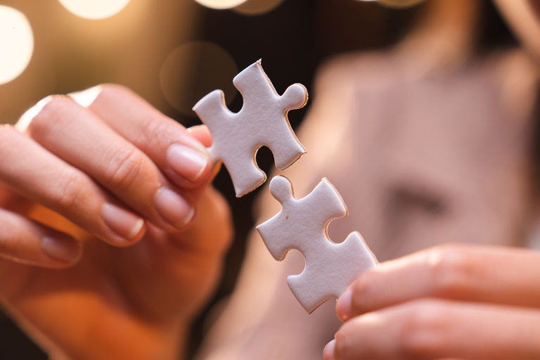 Woman trying to connect 2 pieces of a white puzzle