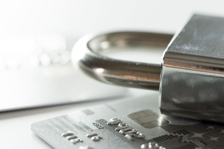 Silver padlock on top of a silver credit card