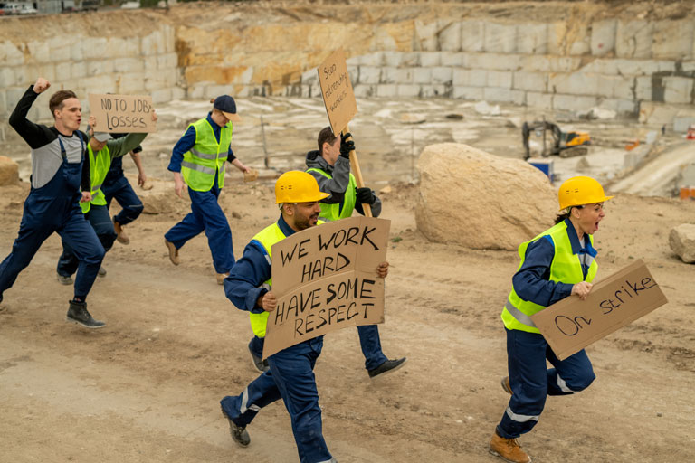 crowd of construction workers protesting at a construction site while holding signs