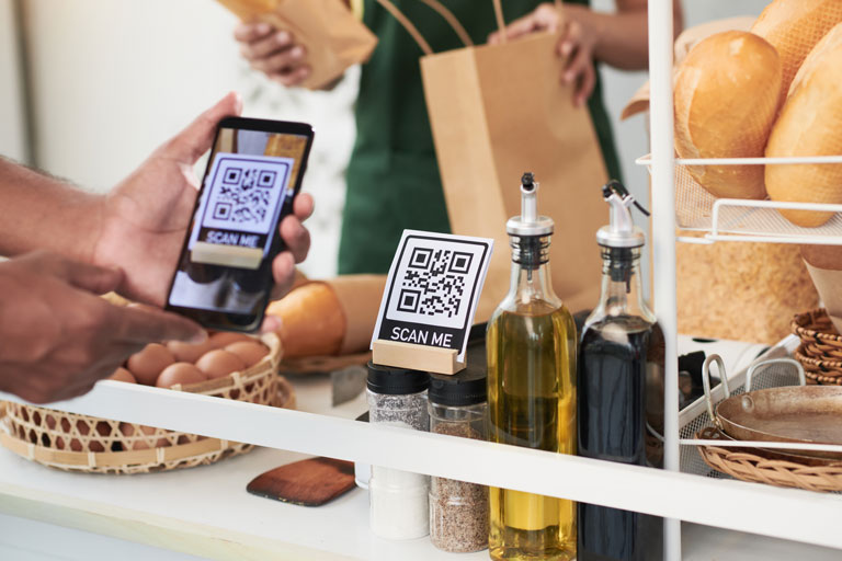 Male Customer at a bakery scanning a QR code with his phone to pay for bread