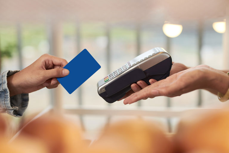 customer swiping a blue credit card on a payment machine